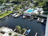 Aerial perspective of the deep-water marina featuring multiple boat slips, a swimming pool, a covered pavilion, and hard-court tennis facilities