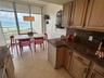 Kitchen featuring wood cabinetry, stone countertops, tiled flooring, pendant lighting, and floor-to-ceiling glass windows