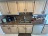 Light-toned wood cabinetry with matte black hardware, stone-finish countertops, dual-basin stainless steel sink, pull-down faucet, and integrated stai