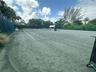 Tennis court with green synthetic surface, perimeter mesh fencing, and net system
