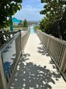 Elevated wooden boardwalk featuring perimeter railings and a covered entry archway leading to the beach