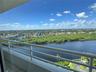 Covered balcony with white metal railing overlooking a large expanse of water and lush coastal landscape