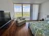 Floor-to-ceiling glass sliding doors with vertical blinds, private balcony, and wood-finish flooring