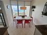 Floor-to-ceiling windows featuring ocean scenery, tile flooring, and a drum pendant light fixture