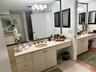 Bathroom featuring a dual-vanity setup with stone countertops, undermount sinks, wall-to-wall mirrors, and built-in cabinetry with metallic hardware