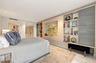 Built-in light wood cabinetry featuring open display shelving and recessed television mount, stone-finish flooring, and recessed ceiling lighting