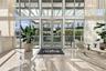 Floor-to-ceiling glass wall, double glass entry doors, expansive polished stone flooring, and high-reaching structural beams
