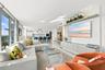 Floor-to-ceiling glass windows, recessed ceiling lighting, stone-finish flooring, custom built-in media cabinetry, and an open-concept kitchen with st