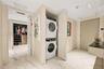 Stacked laundry unit housed in a dedicated closet, polished stone-finish flooring, and built-in closet shelving with integrated drawers
