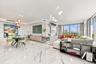 Open-concept living space featuring large-format veined tile flooring, built-in recessed cabinetry, floor-to-ceiling windows, and recessed lighting