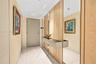 Entryway featuring large-format white tile flooring, vertical wood slat wall paneling, floor-to-ceiling mirror accents, and a built-in wall-mounted co