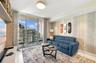 Living area featuring floor-to-ceiling glass sliding doors, built-in open-shelf cabinetry, textured accent wall, polished tile flooring, and flush-mou