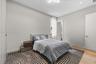 Neutral-toned bedroom featuring wood-finish flooring, recessed lighting, a modern geometric ceiling light fixture, and floor-to-ceiling cabinetry