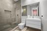 Modern bathroom featuring a glass-enclosed shower with tiled walls and a built-in recessed niche, a white floating vanity with a seamless integrated s