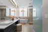 Modern bathroom featuring a floating dual vanity with rectangular vessel sinks, wall-mounted faucets, a freestanding soaking tub, and a glass-enclosed