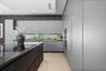 Contemporary kitchen featuring flat-panel cabinetry, a dark-toned center island with a stone-surface countertop, integrated stainless steel appliances