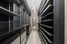 Custom walk-in storage area featuring dark-toned built-in cabinetry, integrated glass shelving, sleek flat-front drawers, a full-length wall mirror, a