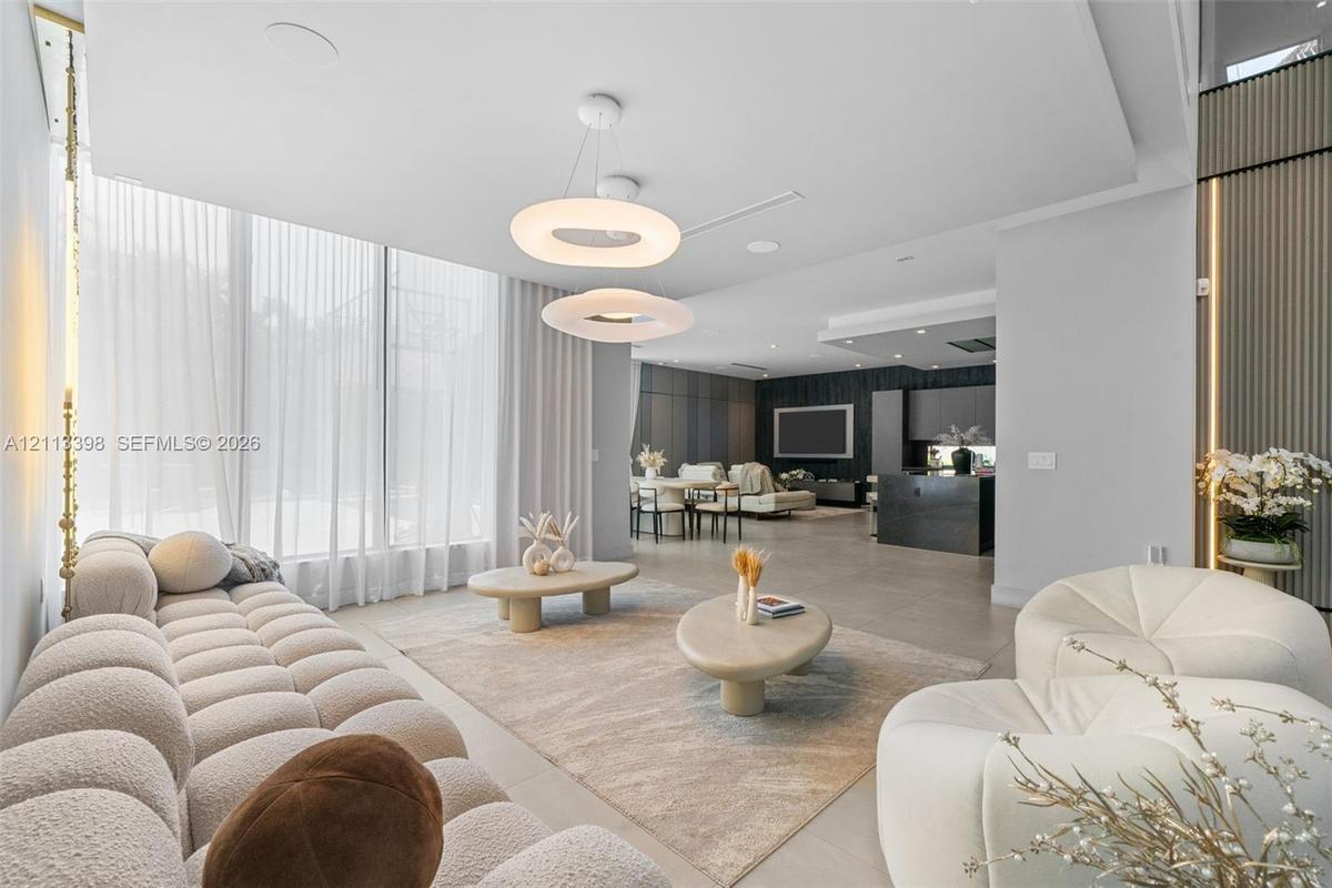 Open-concept interior featuring floor-to-ceiling windows, modern circular pendant lighting, large-format tile flooring, and vertical wall paneling wit