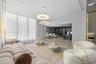 Open-concept interior featuring floor-to-ceiling windows, modern circular pendant lighting, large-format tile flooring, and vertical wall paneling wit