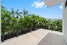 Covered balcony featuring concrete flooring, a dark metal cable railing, and dense mature palms