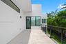 Covered exterior terrace featuring a smooth concrete floor, minimalist white stucco exterior walls, dark-framed expansive windows, and a metal horizon