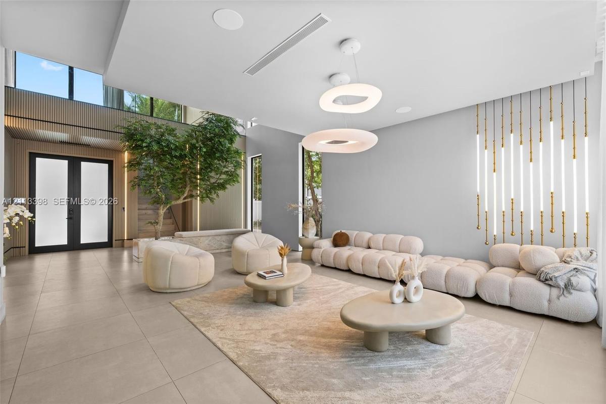 Open-concept interior featuring large-format tile flooring, double-height ceilings, vertical wall-mounted linear light fixtures, circular tiered penda