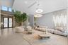 Open-concept interior featuring large-format tile flooring, double-height ceilings, vertical wall-mounted linear light fixtures, circular tiered penda