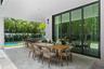 Covered patio featuring stone-tile flooring, floor-to-ceiling glass sliding doors, recessed lighting, and a built-in outdoor kitchen with a stone coun