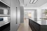 Kitchen featuring stainless steel built-in microwave and oven, floor-to-ceiling matte cabinetry, stone-surfaced kitchen island with integrated cooktop