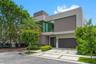 Modern multi-level exterior featuring smooth stucco facade, floor-to-ceiling glass windows, integrated covered entryway, and segmented concrete paver 