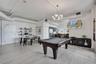 Open-concept living space featuring wood-finish flooring, exposed industrial-style ductwork, a modern multi-bulb chandelier, and high ceilings