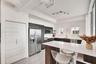 Kitchen featuring flat-panel cabinetry, quartz countertops, stainless steel appliances, track lighting, and wood-finish cabinetry on the island