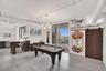 Open-concept living space featuring wood-finish flooring, exposed overhead industrial piping, a multi-globe chandelier, and a wood-panel sliding barn 
