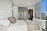 Floor-to-ceiling windows, sliding glass door access to an exterior balcony, industrial-style exposed ceiling, and built-in dark wood cabinetry