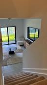 Interior space featuring neutral-toned carpeting on stairs, large-format tile flooring, and a sliding glass door providing external access