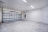 Garage interior featuring concrete flooring, LED strip lighting, an integrated electrical panel, and a paneled roll-up garage door