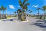 Gated community entrance featuring automated security gates, perimeter metal fencing, and palm-lined landscaping