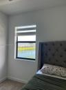 Neutral-toned walls, carpeted flooring, and a window featuring a dual-layer roller shade