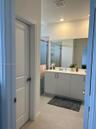 Dual-sink vanity with light-toned cabinetry, light-colored countertops, large wall-mounted mirror, and glass-enclosed shower featuring tile surrounds