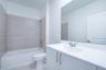 Bathroom featuring a white vanity cabinet with a solid surface countertop, an undermount sink with chrome fixtures, a full-width wall mirror, and a ti