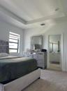 Tray ceiling, neutral carpeting, and window with horizontal blinds