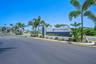 Gated entrance featuring professional hardscaping, manicured landscaping, and mature palm trees