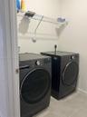 Laundry area featuring large-format neutral tile flooring and overhead wire shelving