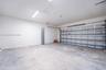 Finished garage featuring smooth-finish walls, exposed panel-style garage door, concrete flooring, and overhead lighting