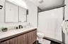 Bathroom featuring a wood-finish floating vanity, integrated rectangular sink, matte black widespread faucet, and expansive mirrored medicine cabinet