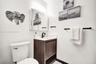 Wood-finish vanity with a stone-top sink, matte black faucet, mirrored medicine cabinet, and matte black towel hardware