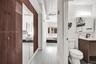 Floor-to-ceiling cabinetry with mirrored doors, wood-finish flooring, industrial exposed ductwork, and vanity with an integrated sink and matte black 