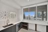 Kitchen featuring expansive window walls, stainless steel undermount sink with gooseneck faucet, integrated dishwasher, dark cabinetry with flat-panel