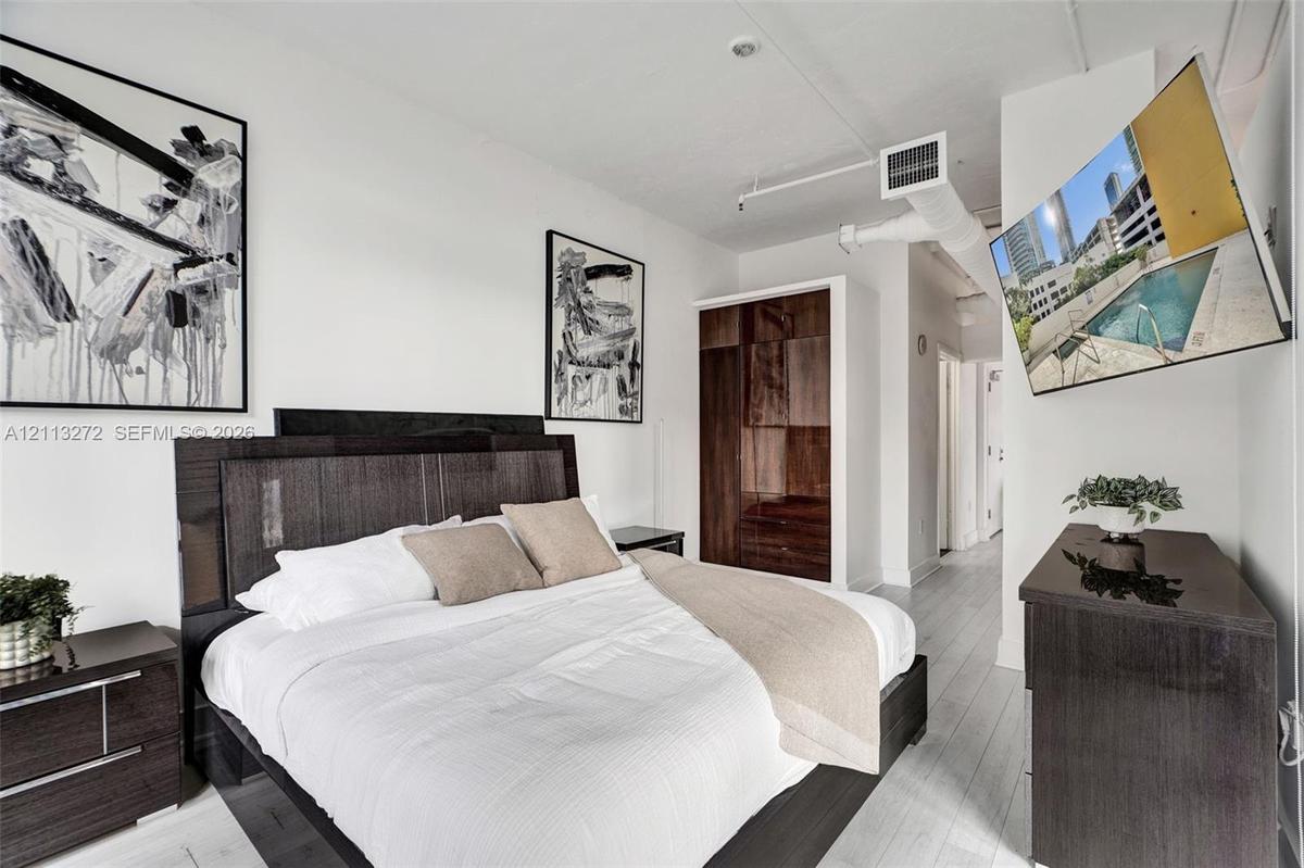 High-ceiling loft featuring exposed ductwork, white wood-finish flooring, and built-in dark wood cabinetry