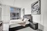 Expansive floor-to-ceiling glass sliding doors, neutral light-toned wood-finish flooring, and high ceilings